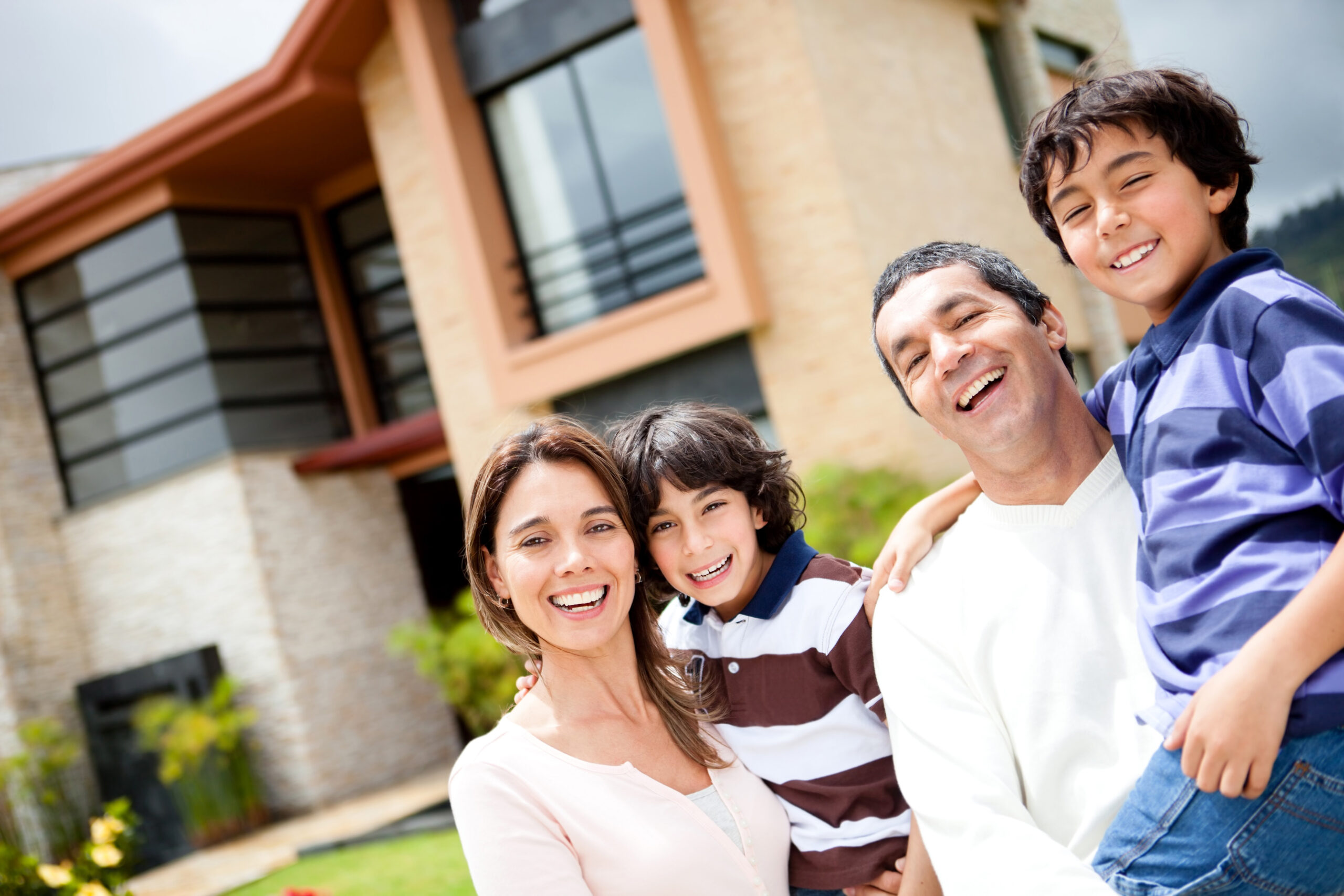 happy family in front of a big home