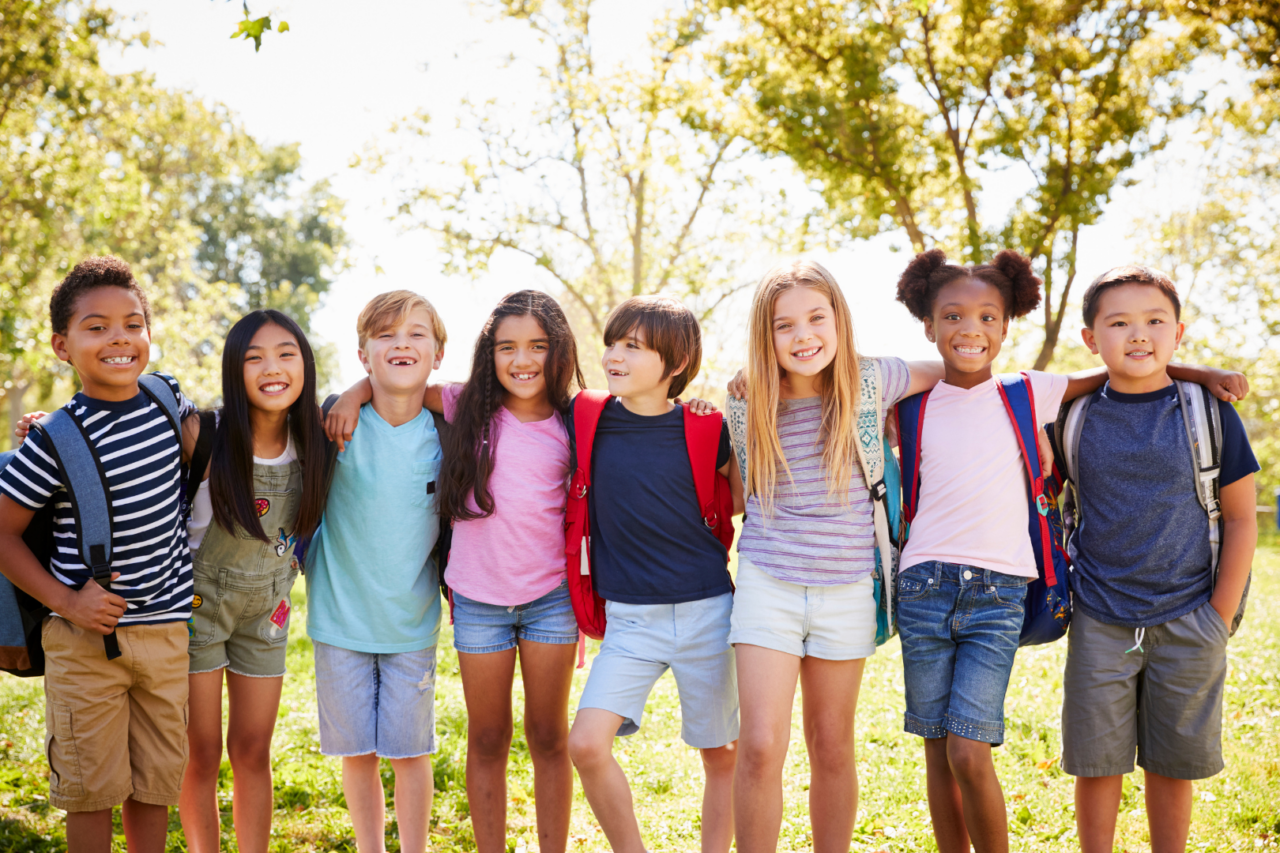 children wearing backpacks smiling together