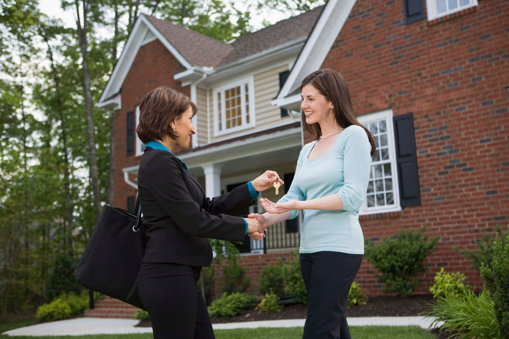 realtor handing homeowner the keys to their new home