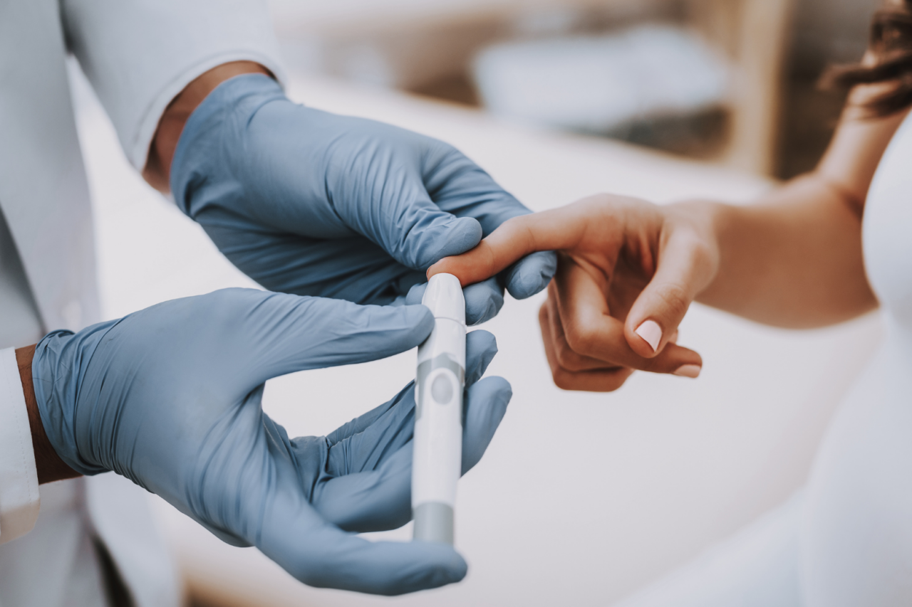 doctor pricking diabetes patient's finger